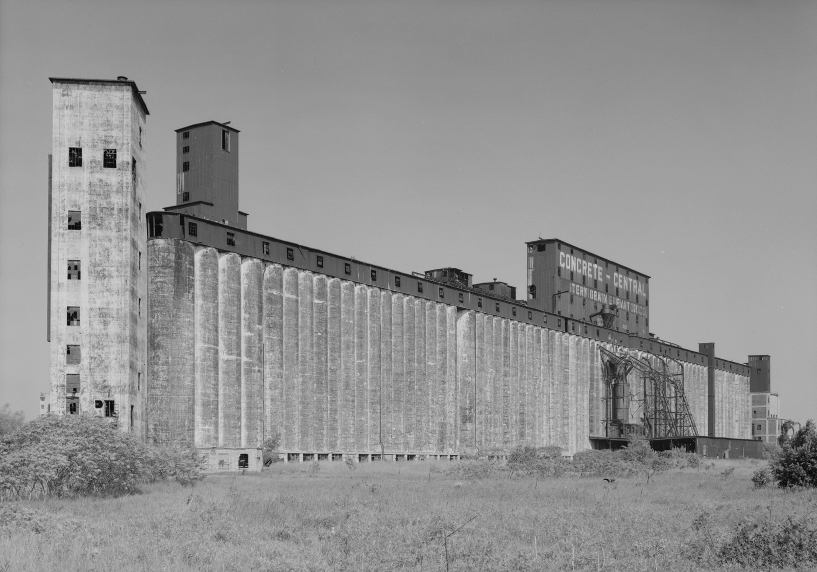 Black-and-white archival photograph of Concrete-Central Elevator, with a long row of cylindrical concrete bins and taller rectangular towers.